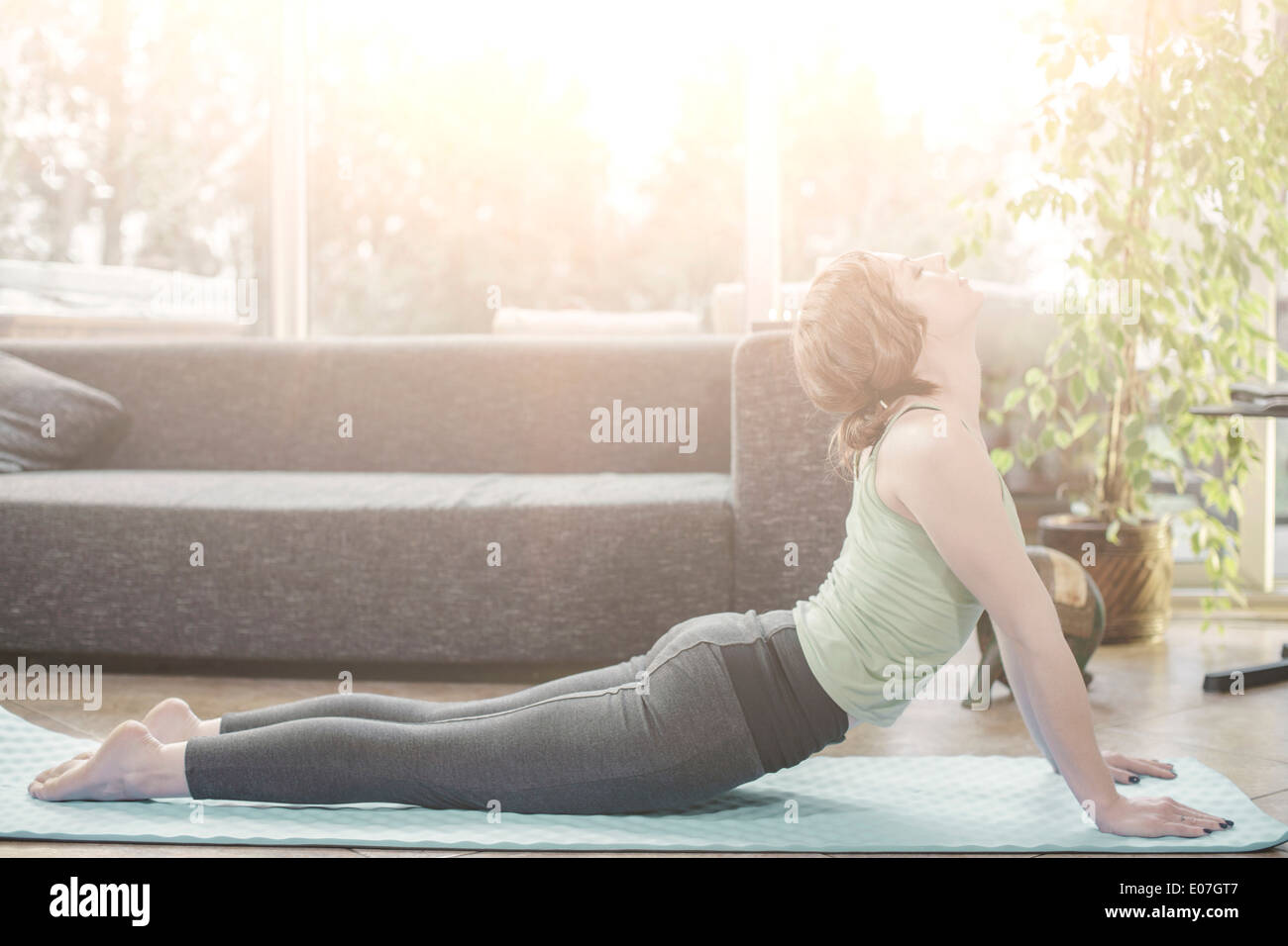 Giovane donna facendo esercizio di yoga a casa Foto Stock