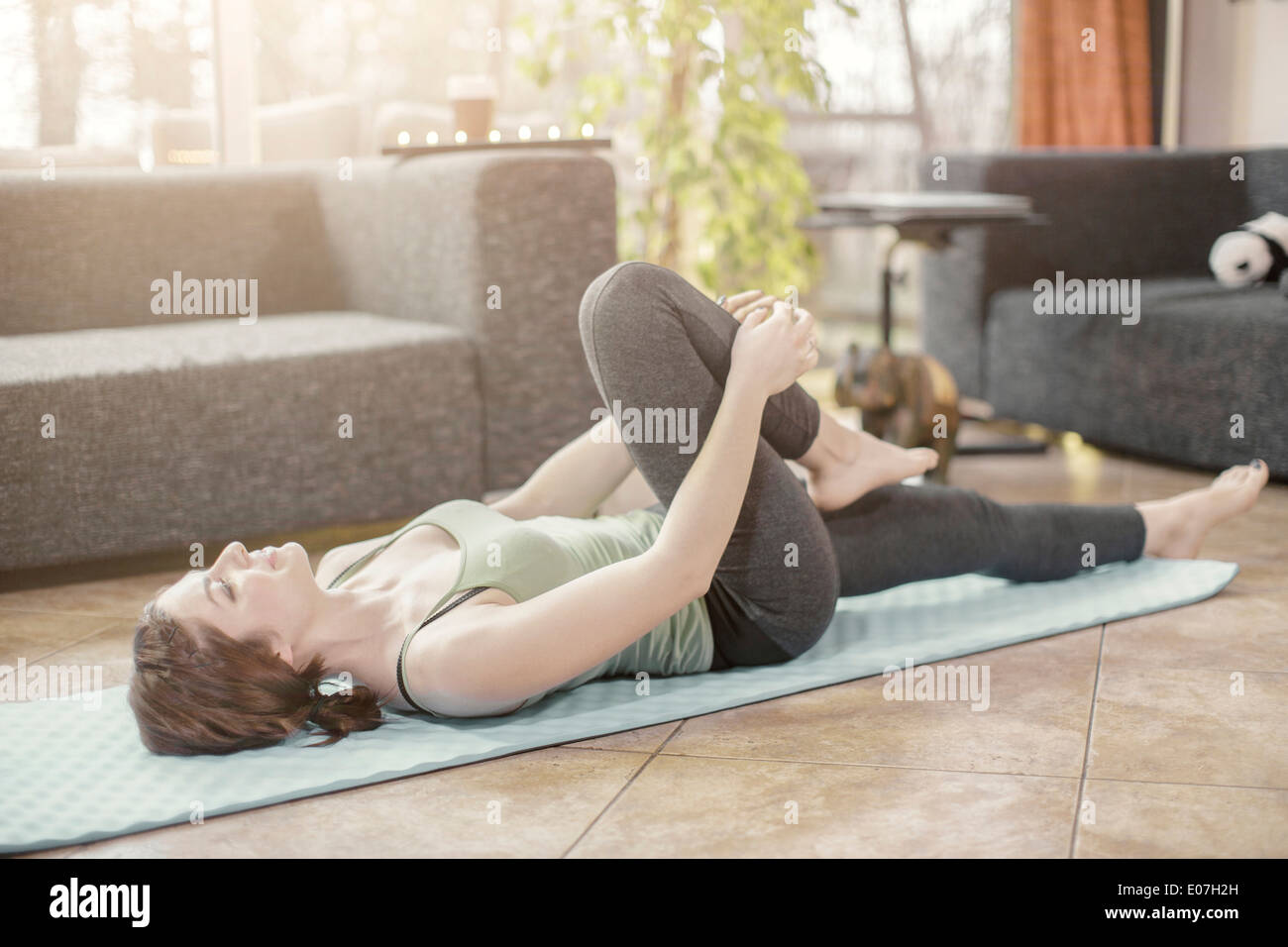 Giovane donna facendo esercizio di yoga a casa Foto Stock