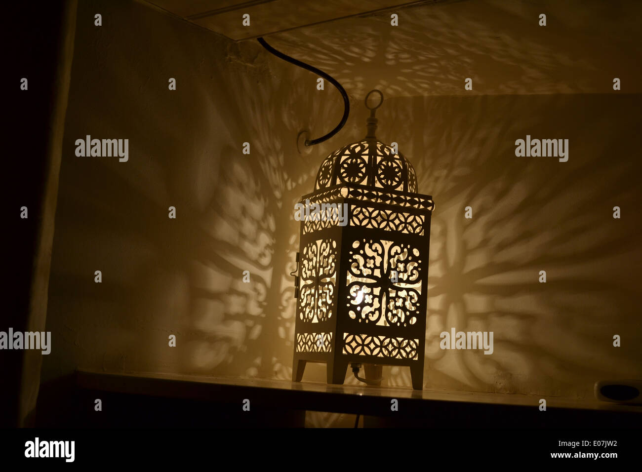 La Lampada sul ripiano in angolo con il modello riflesso sulla parete Foto Stock