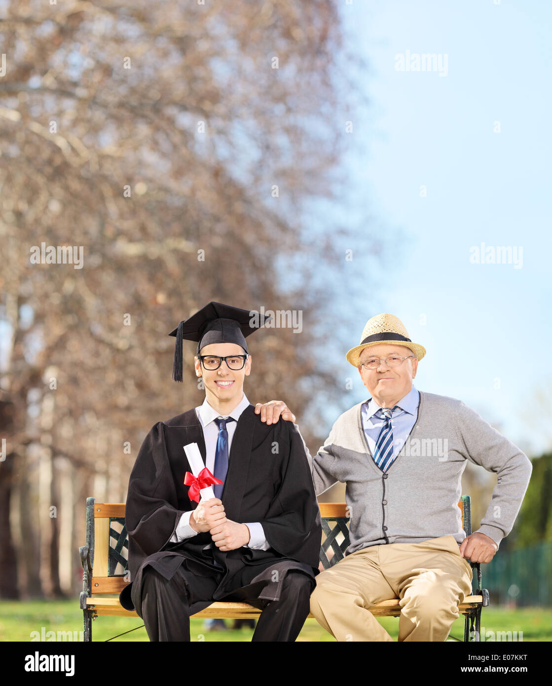 Laureati maschi in posa con il suo padre orgoglioso in posizione di parcheggio Foto Stock