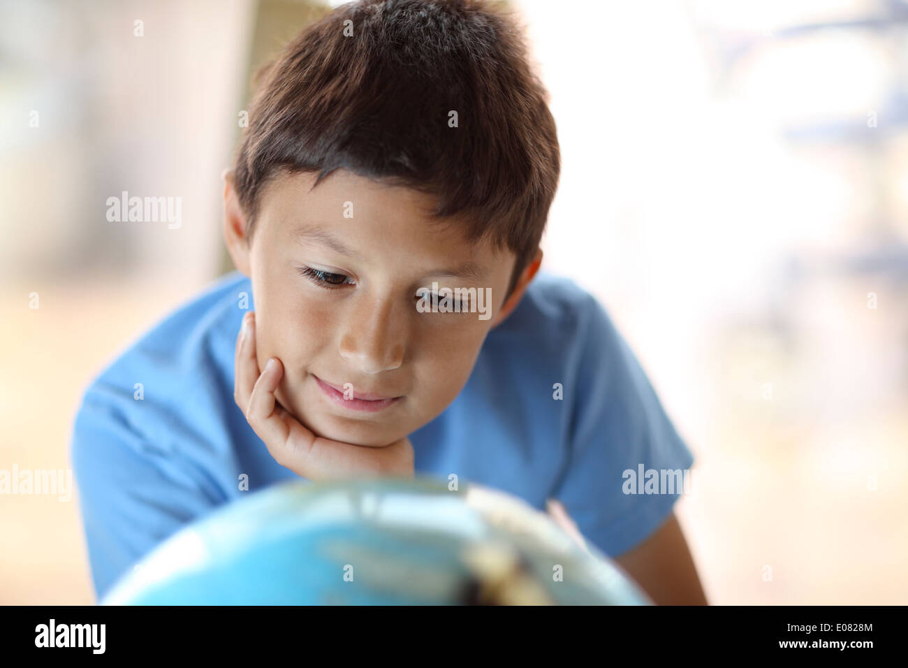 Y0oung ragazzo sogna di viaggiare come egli guarda un globo Foto Stock
