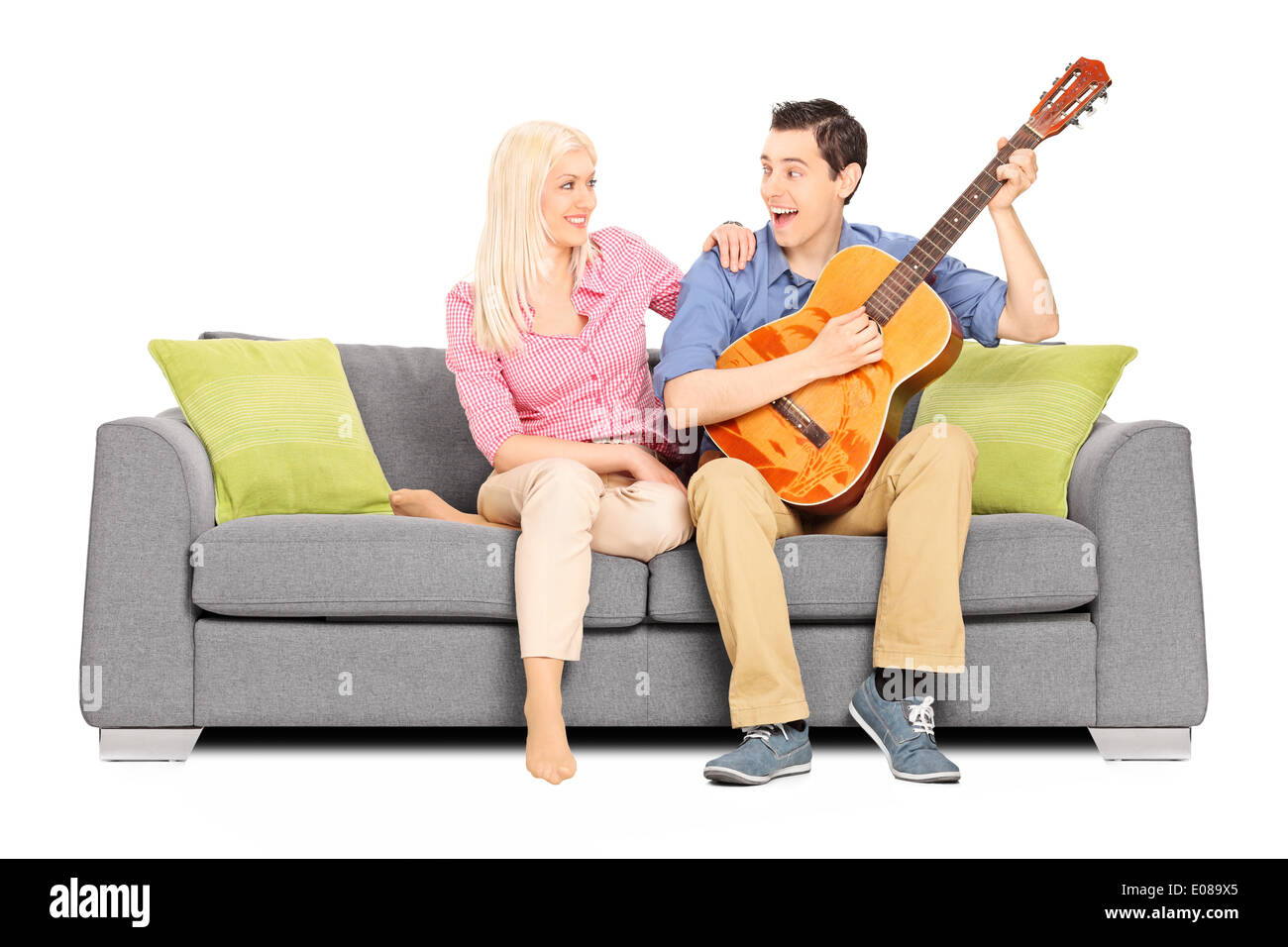 L'uomo gioca su chitarra con la sua ragazza seduta sul divano Foto Stock