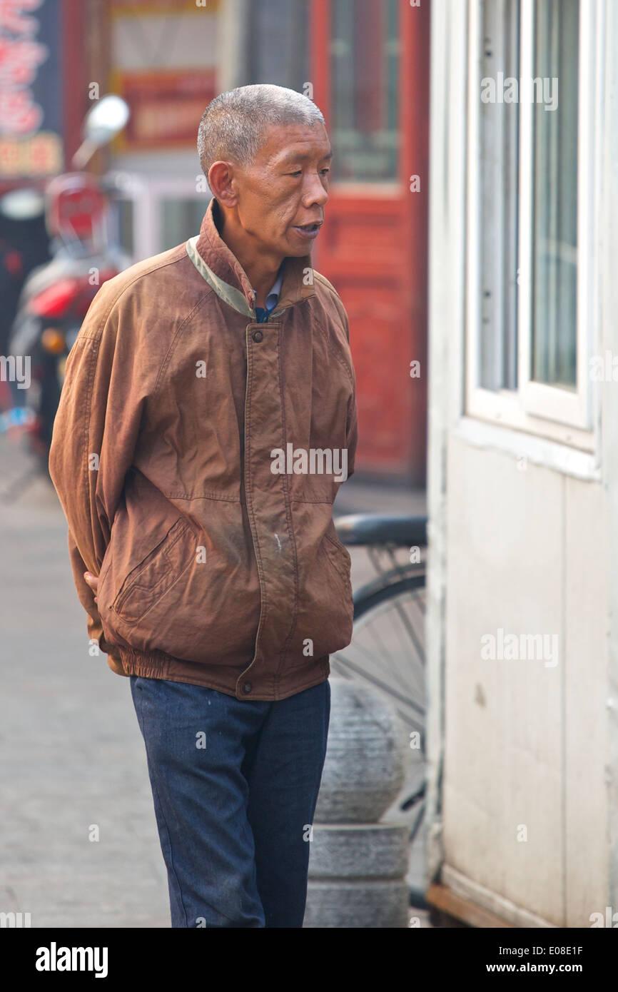 Anziani uomo cinese a piedi attraverso la storica Hutong di Da Shi Lan, Pechino, Cina. Foto Stock