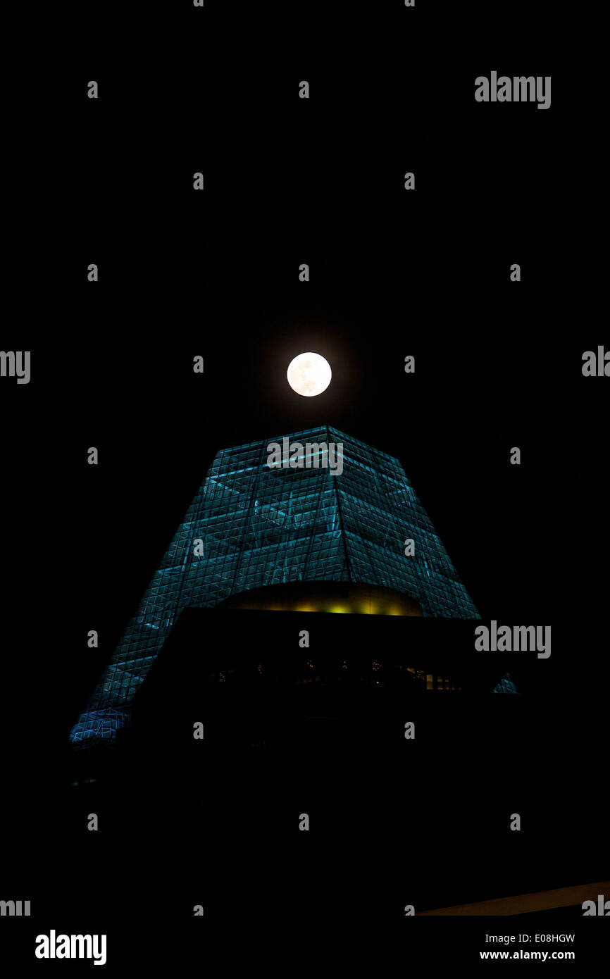 In Allineamento, Luna Piena al di sopra di un edificio alto e moderno in Singapore. Foto Stock