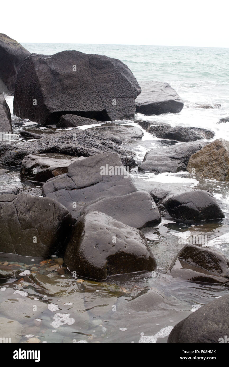 Dettaglio delle rocce nere a bordo dell'acqua / marea a Porth Ysgo, Aberdaron - una piccola baia, spiaggia Foto Stock