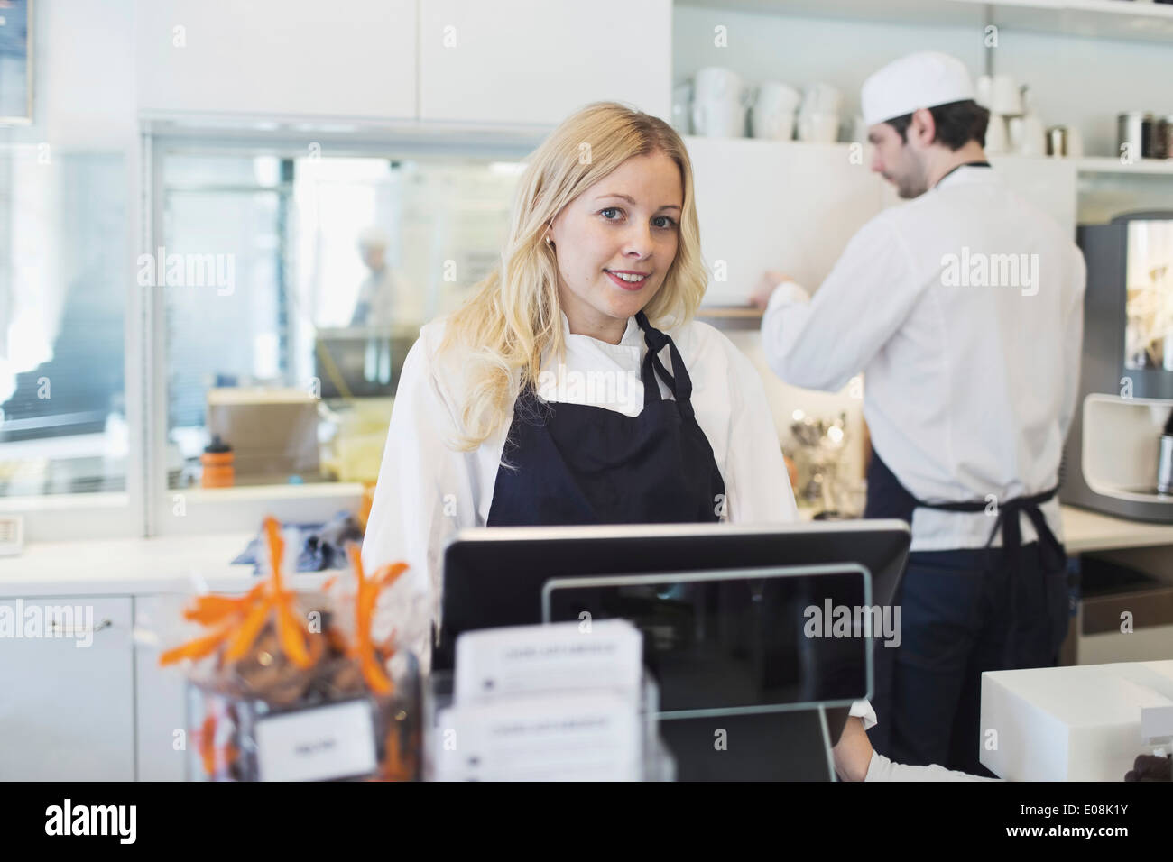 Ritratto di fiducioso proprietario femmina in piedi alla cassa in cafe Foto Stock