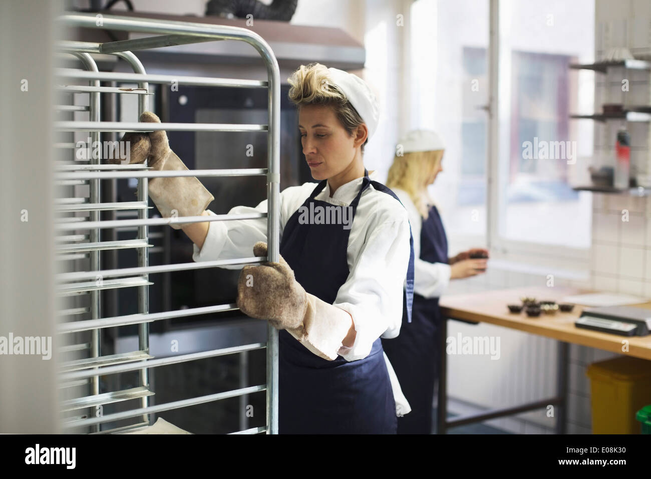 Il panettiere di sesso femminile che lavorano in cucina a forno Foto Stock