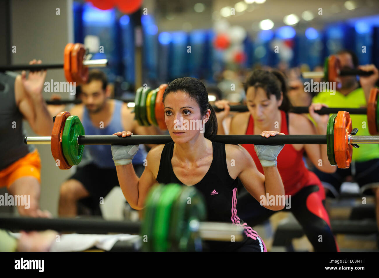 Giovane donna facendo squat durante un corpo pompa classe fitness in palestra Foto Stock