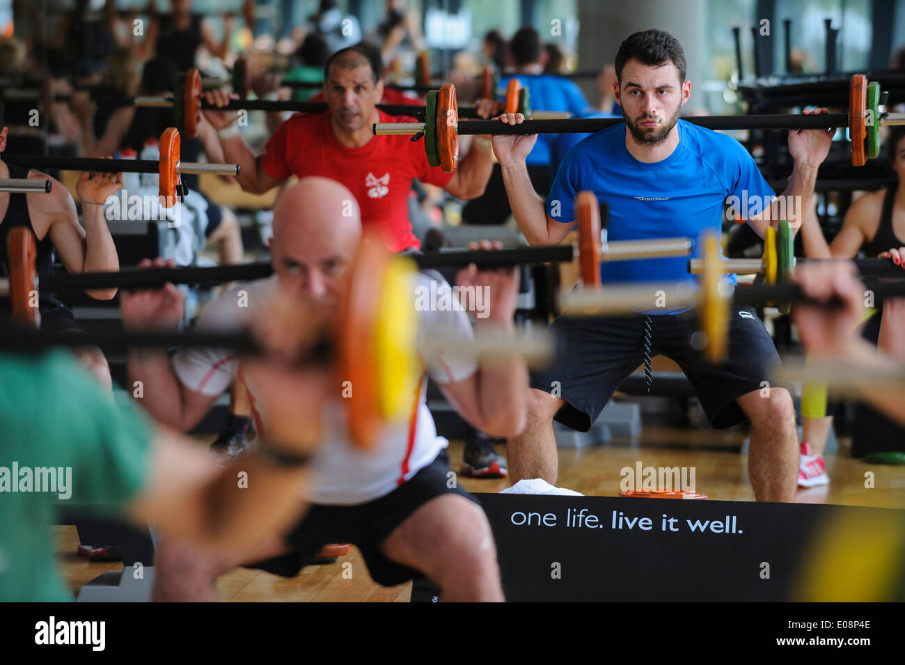 Giovane uomo facendo squat durante un corpo pompa classe fitness in palestra Foto Stock