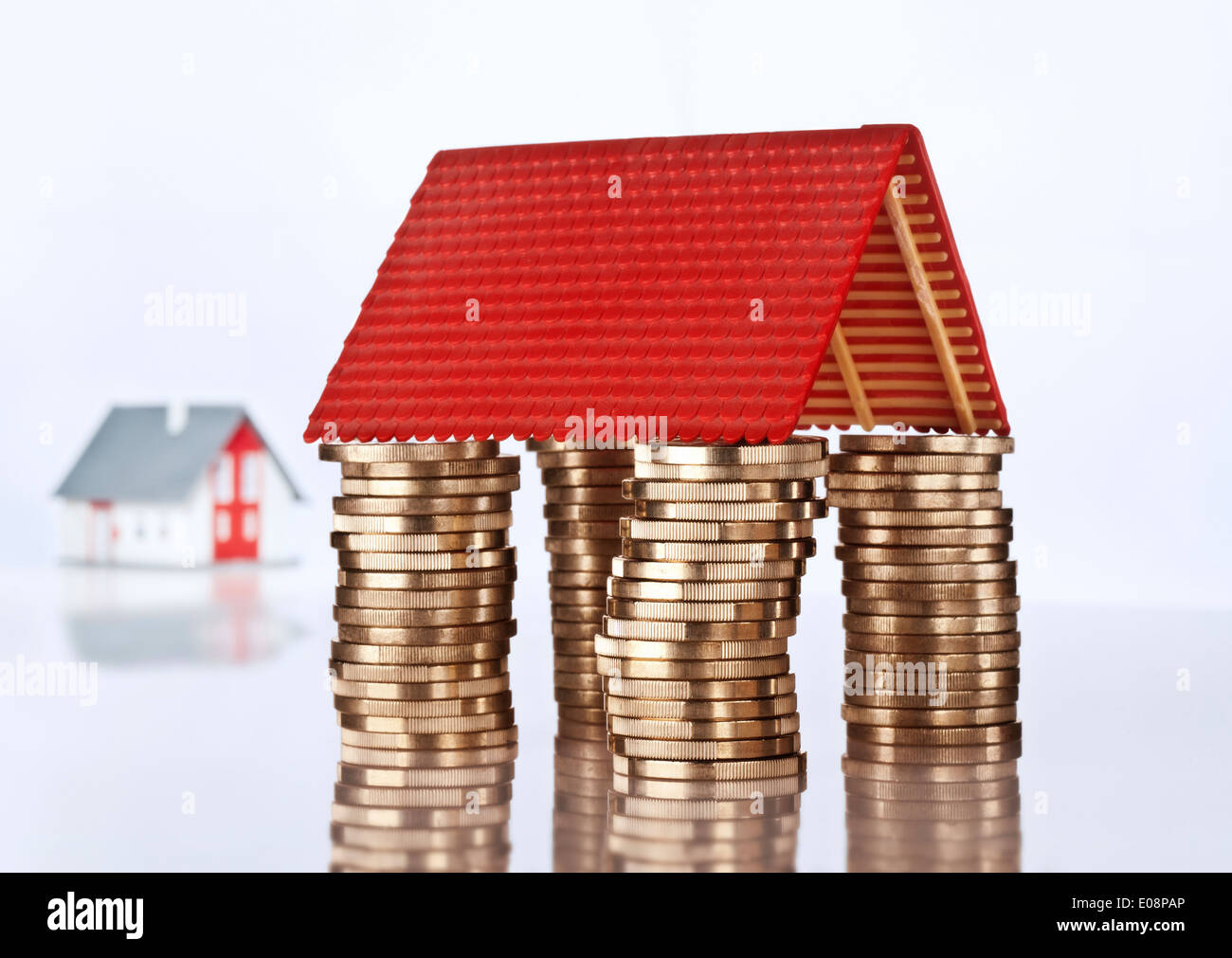 Tetto di un modello di architettura sulla parte superiore di quattro pile di monete. Foto Stock