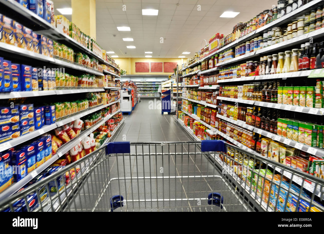 Un carrello vuoto tra gli scaffali del supermercato. Foto Stock