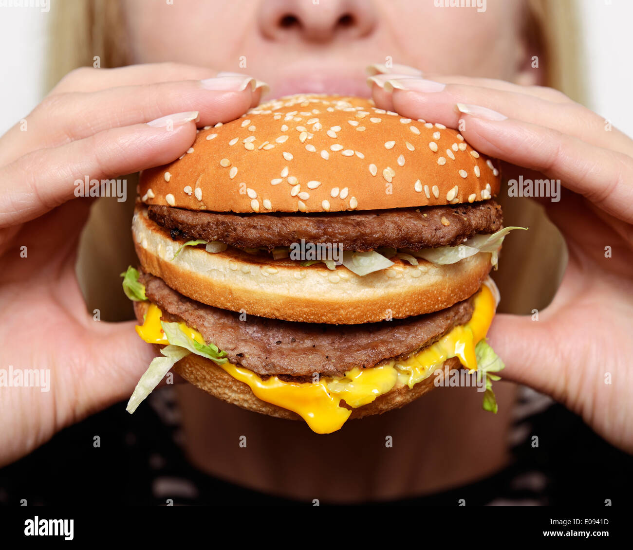 Donna di mangiare un hamburger, vicino. Foto Stock