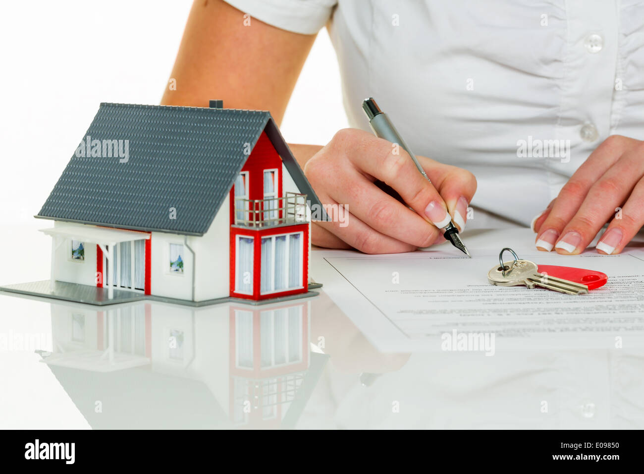 Una donna segni una fattura di vendita per una casa con un agente immobiliare, Eine Frau unterschreibt einen Kaufvertrag fuer ein Haus bei eine Foto Stock