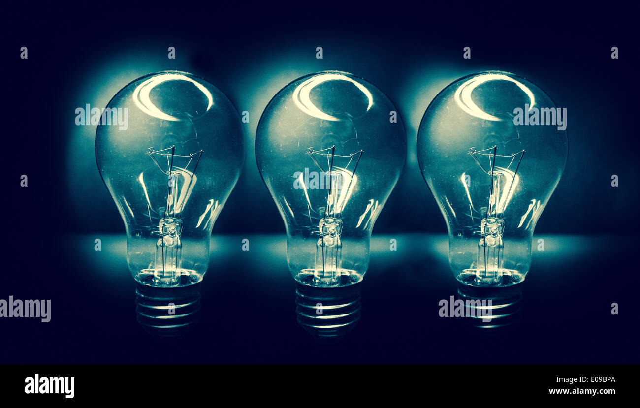 Tre lampadine contro uno sfondo scuro Foto Stock