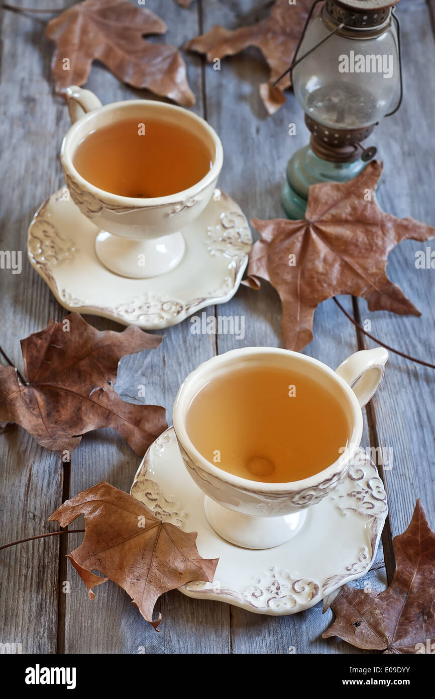 Il tè verde in tazze vintage sul tavolo di legno secco con foglie di autunno. Messa a fuoco selettiva. Foto Stock