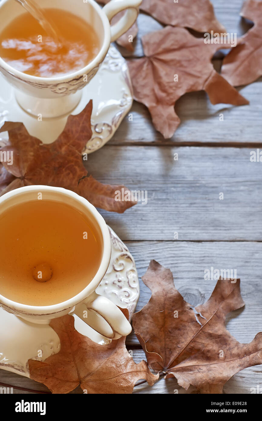 Il tè verde in tazze vintage sul tavolo di legno secco con foglie di autunno. Copia di sfondo spazio. Foto Stock