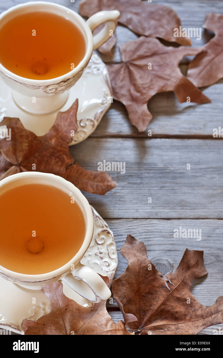Il tè verde in tazze vintage sul tavolo di legno secco con foglie di autunno. Copia di sfondo spazio. Foto Stock