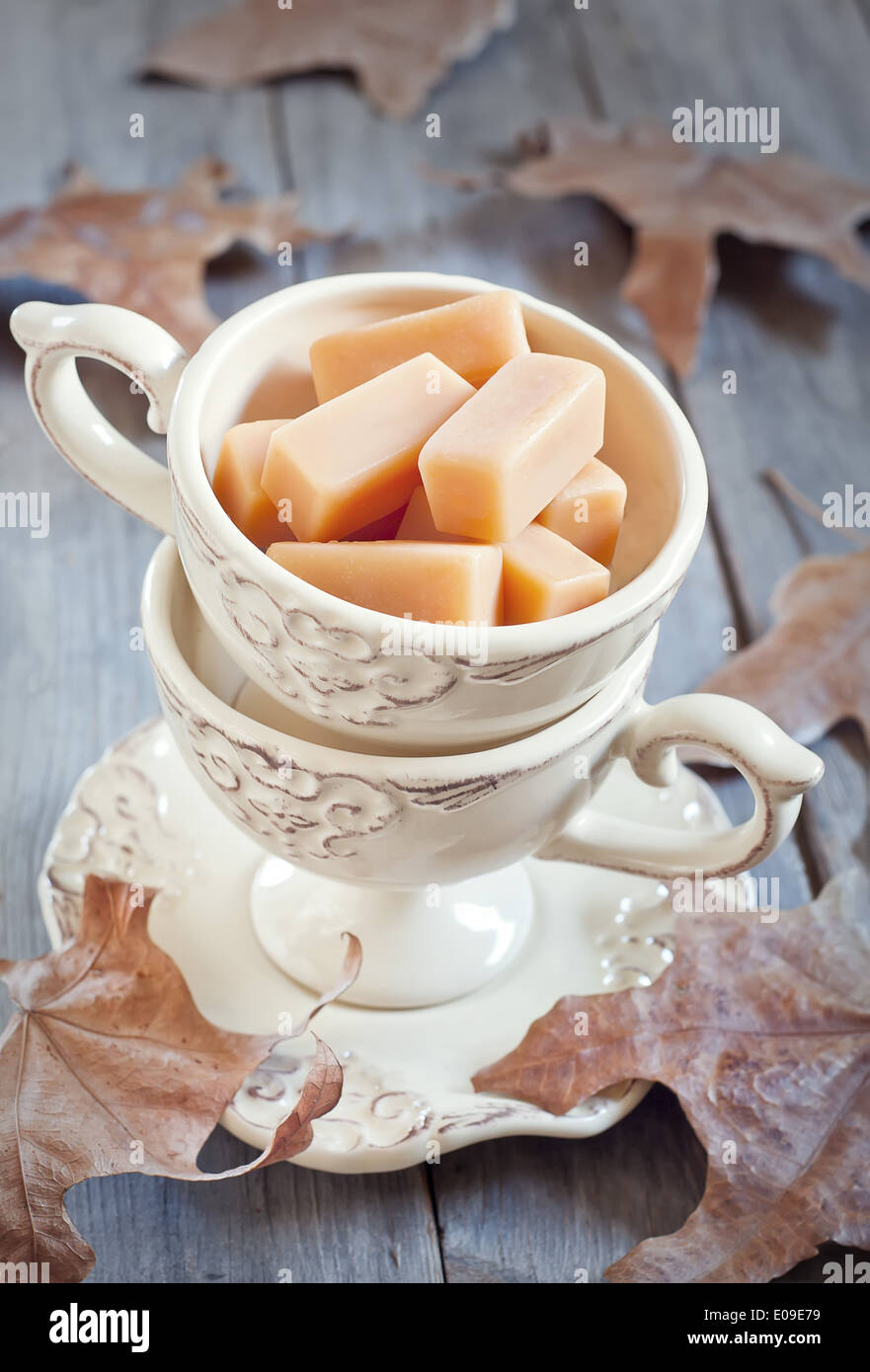 La crema fudge in tazze vintage sul tavolo di legno con foglie di autunno. Messa a fuoco selettiva. Foto Stock