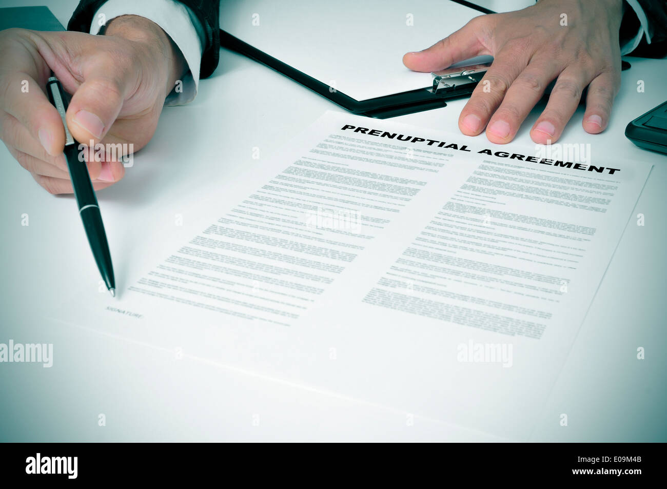 Un uomo che indossa un abito che mostra dove a firmare un accordo prematrimoniali documento Foto Stock