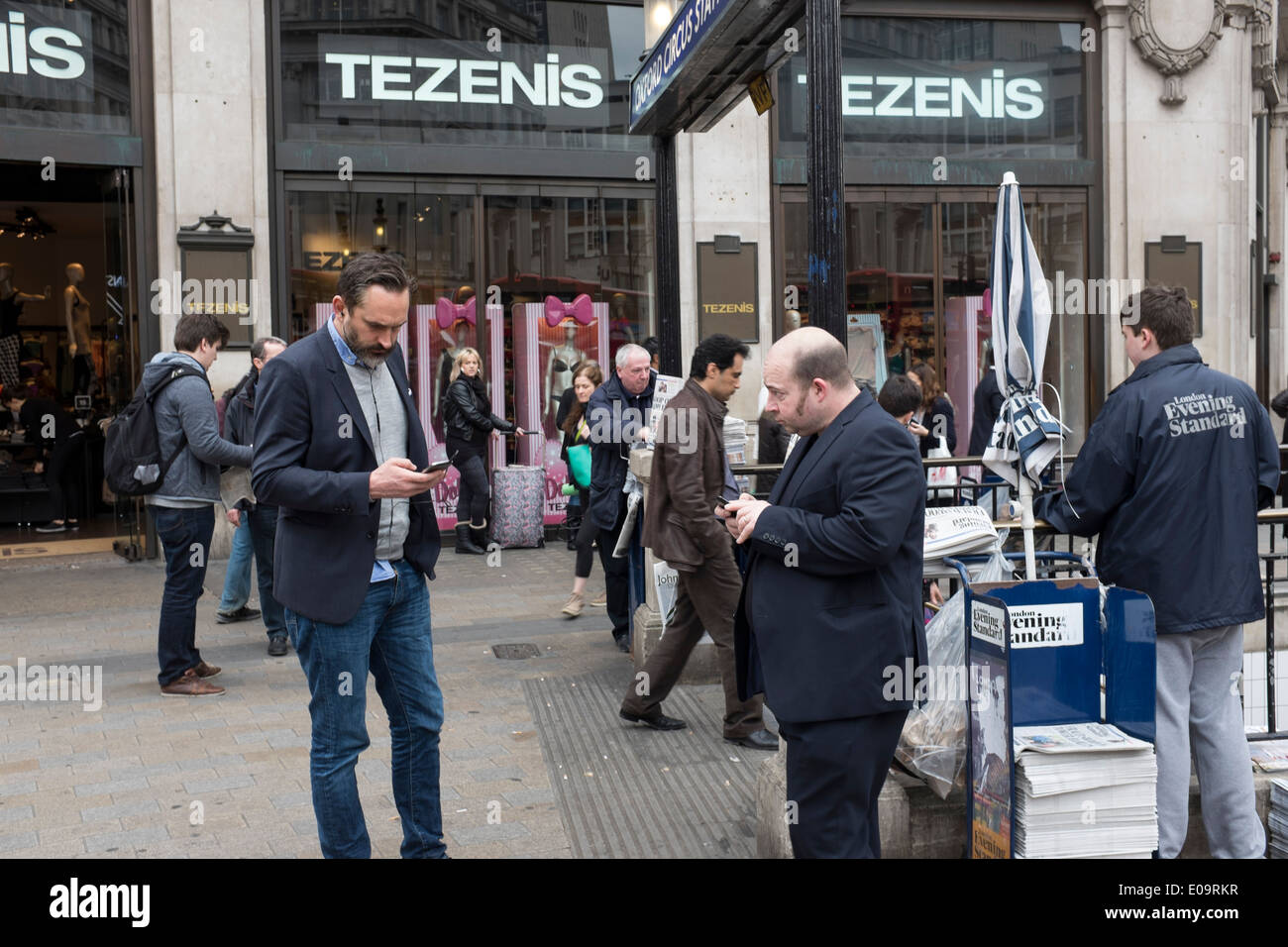 Le persone sui loro telefoni cellulari in Londra principale via dello shopping di Oxford Street Foto Stock