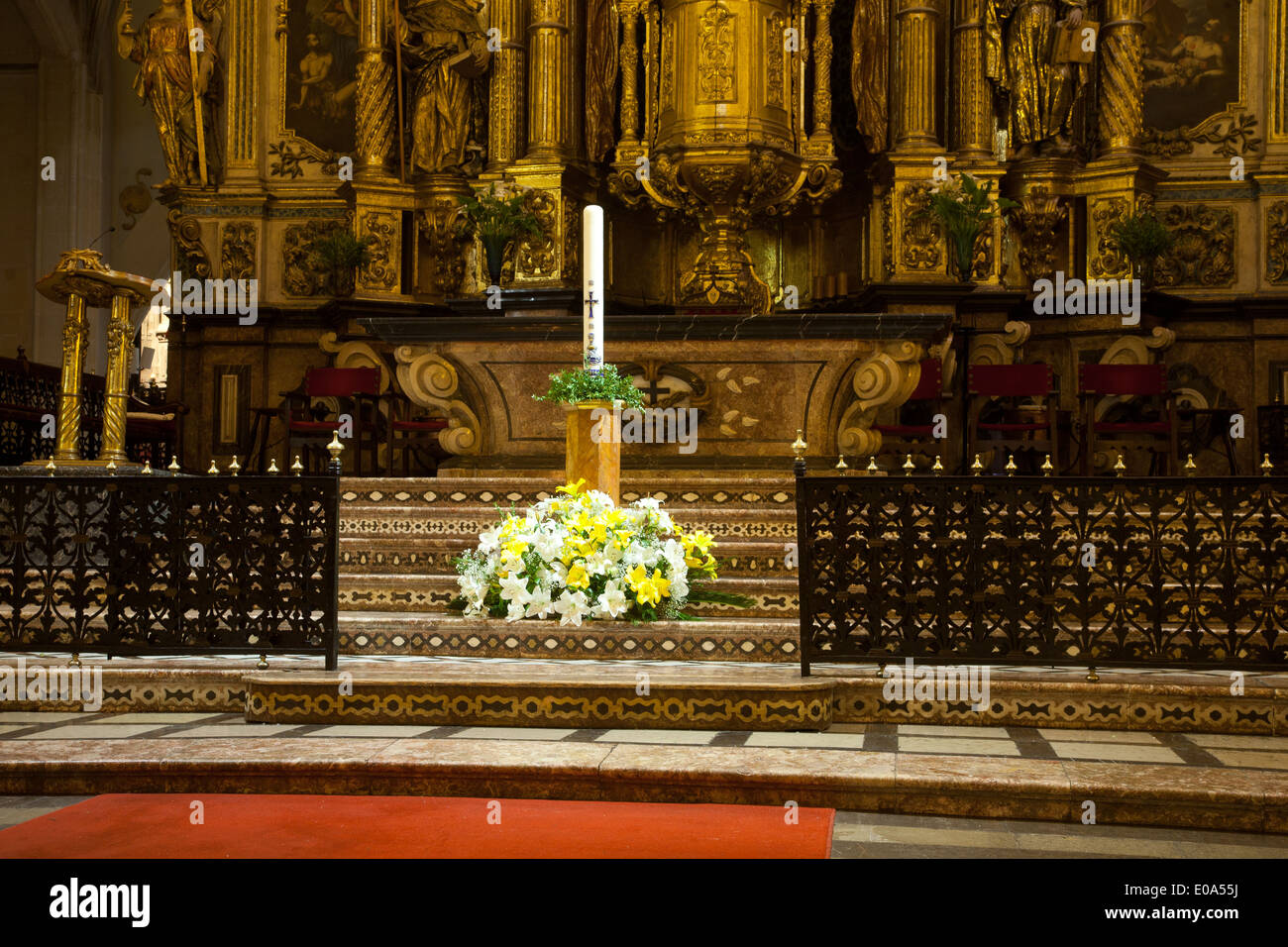 Cero pasquale di fronte all'altare maggiore decorato con gigli nella Basilica di San Francesco in Palma di Mallorca, Spagna Foto Stock