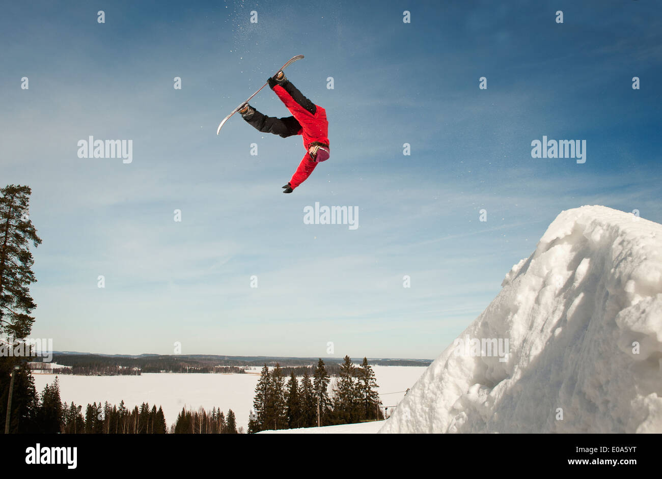 Metà maschio adulto snowboarder capovolto durante la metà del salto in aria Foto Stock