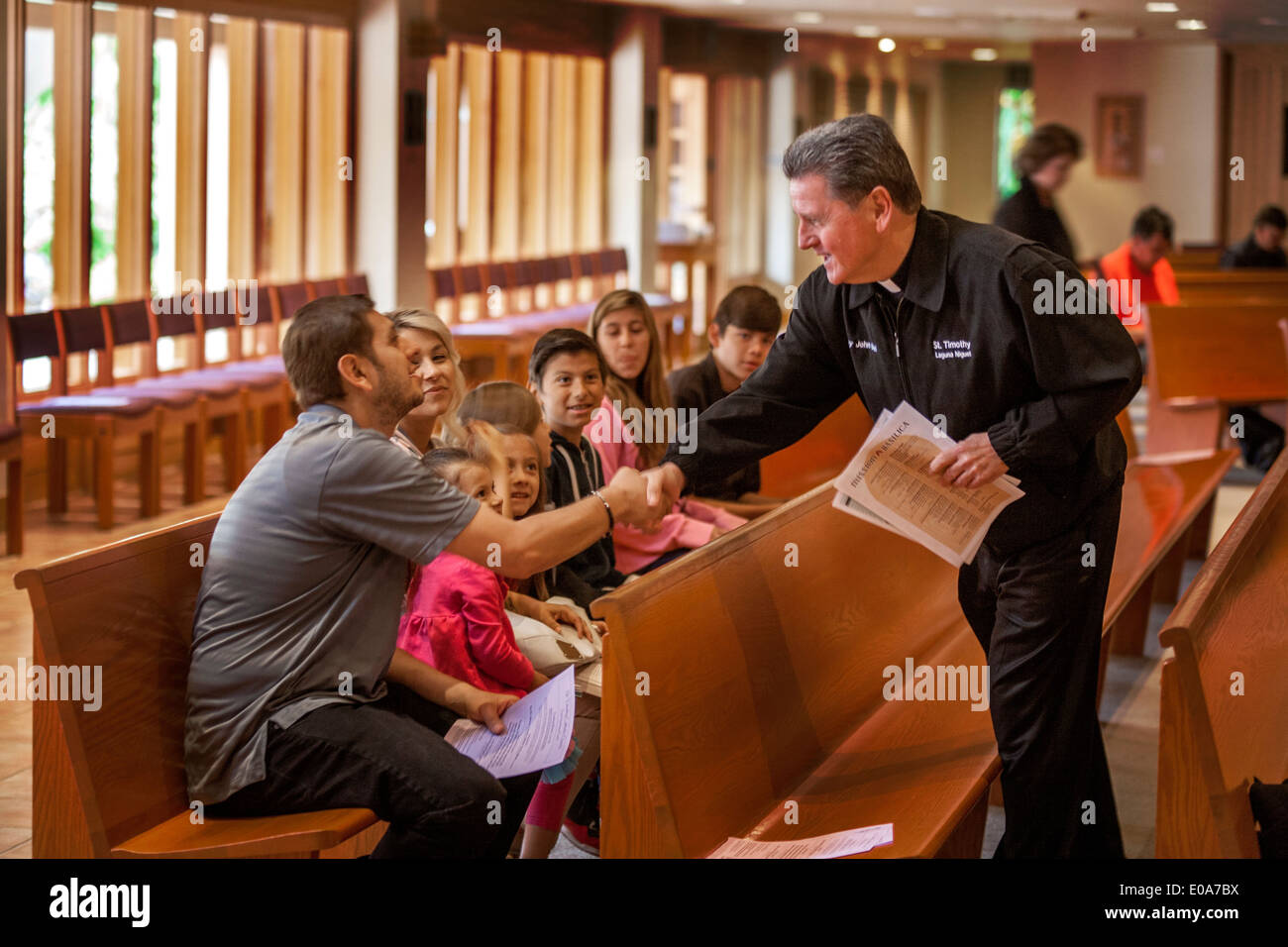 Sacerdote cattolico saluta i giovani ispanici parrocchiani prima messa in una Laguna Niguel, CA, chiesa cattolica. Foto Stock