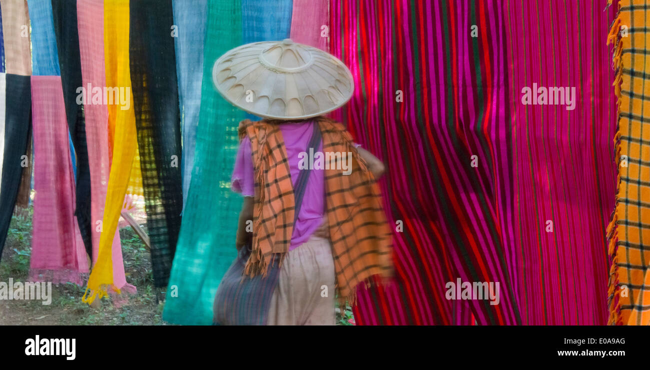 Ragazza camminare da colorate sciarpe di seta su clothline, Lago Inle, Stato Shan, Myanmar Foto Stock