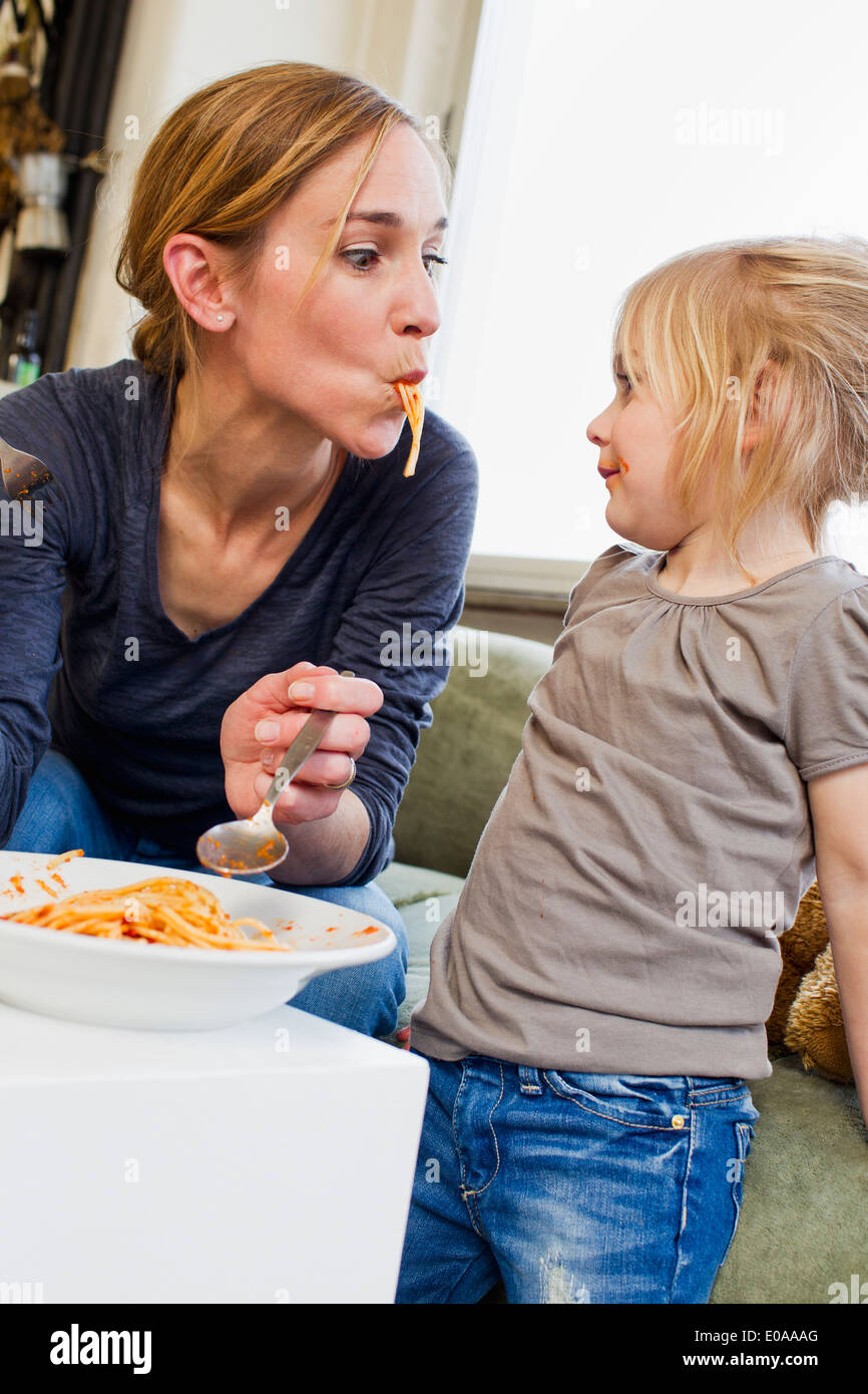 Metà adulto madre mangiare spaghetti con sua figlia Foto Stock