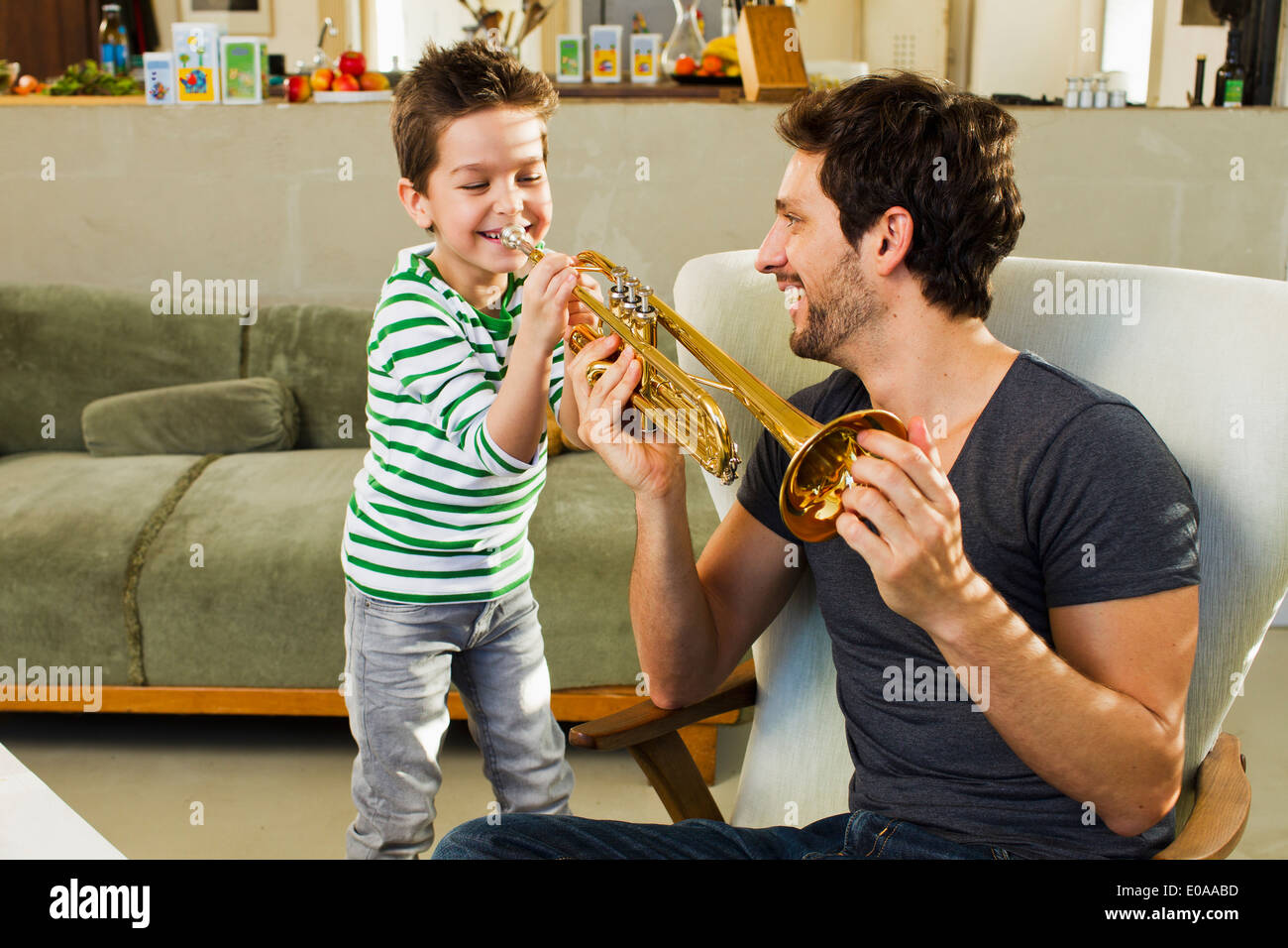 Padre incoraggiando giovane figlio suonare la tromba Foto Stock