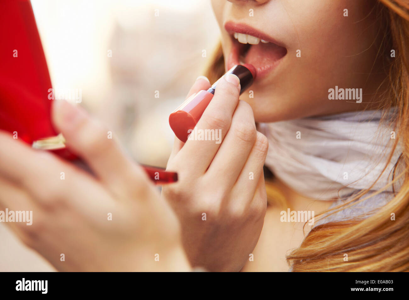Close up della giovane donna mettendo sul rossetto Foto Stock