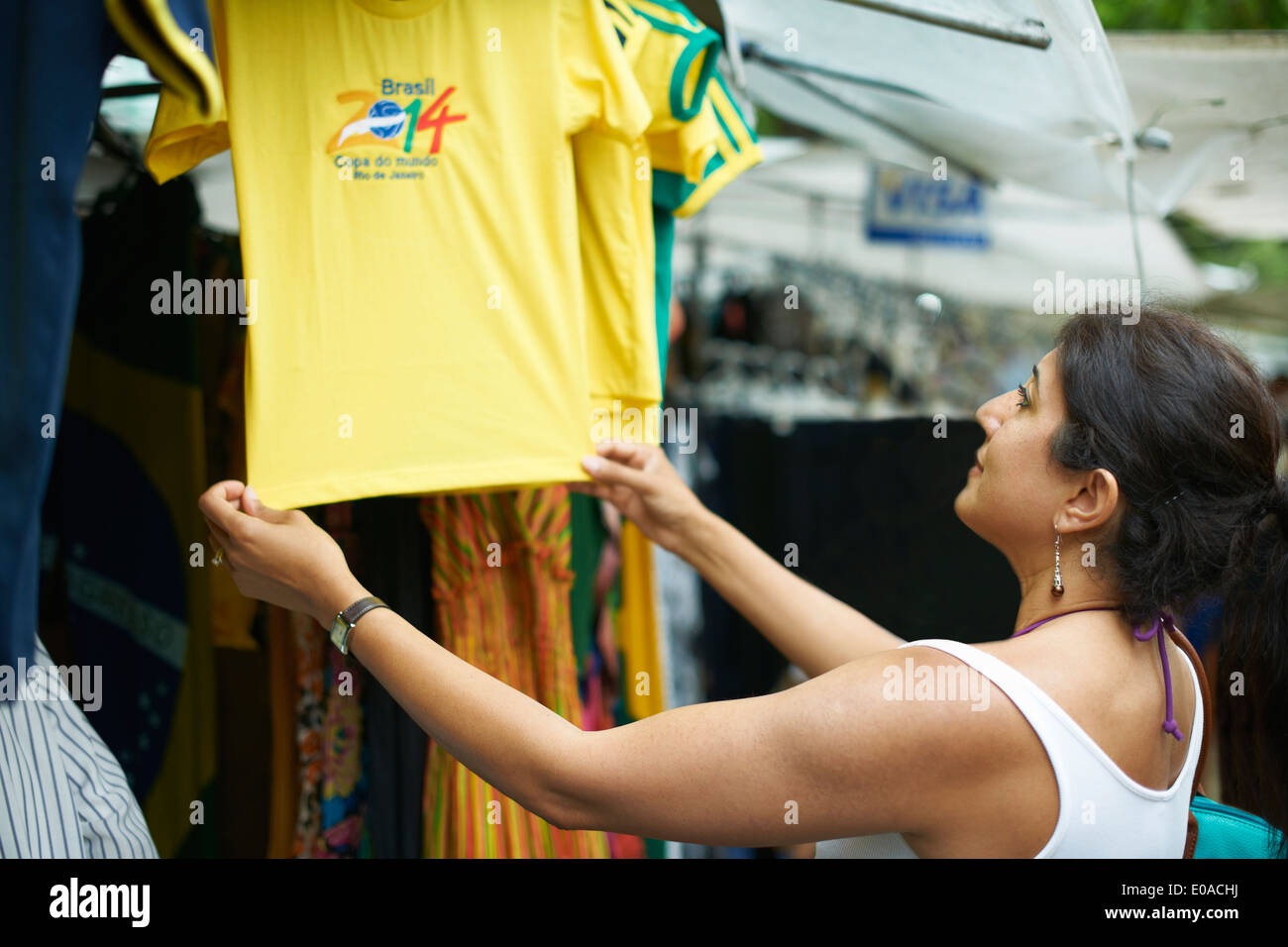 Donna matura guardando il calcio brasiliano t-shirt in stallo del mercato, Ipanema, Rio de Janeiro, Brasile Foto Stock