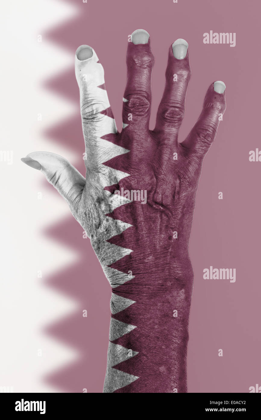 La mano di una vecchia donna avvolta nella bandiera del Qatar Foto Stock