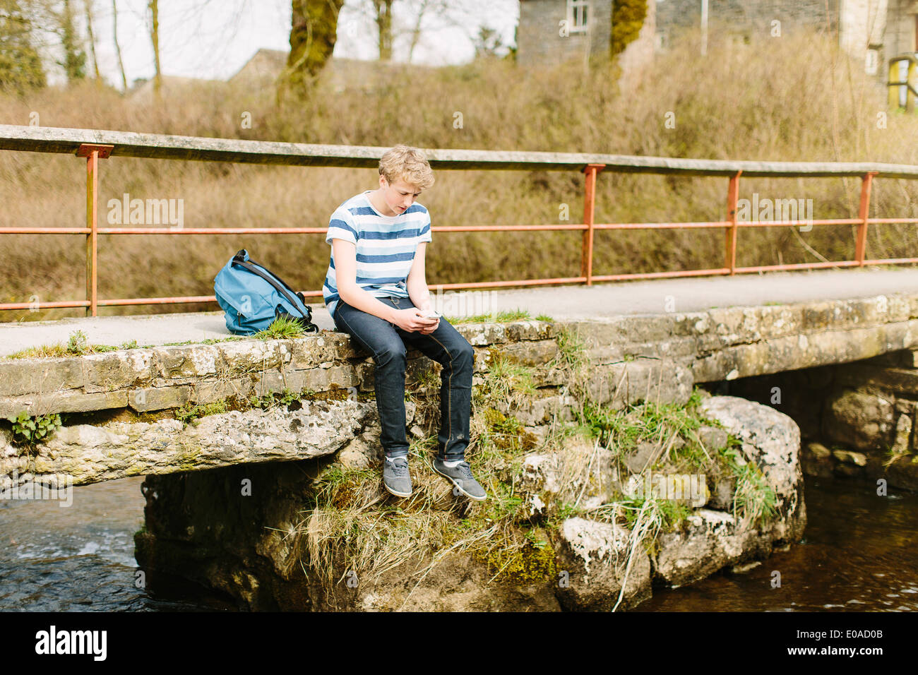 Infelice ragazzo adolescente guardando giù dal ponte rurale Foto Stock