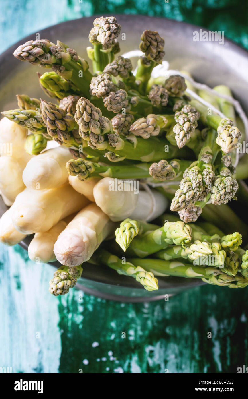 Mazzetto di verde giovane e asparagi bianchi in metallo vintage ciotola verde su un tavolo di legno. Vista superiore Foto Stock