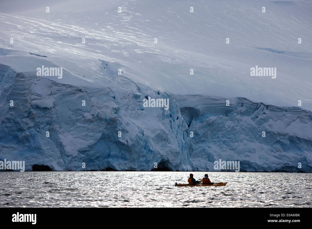 Lone doppia mare canoe kayakers al di sotto del ghiacciaio in Port Lockroy antartide Foto Stock