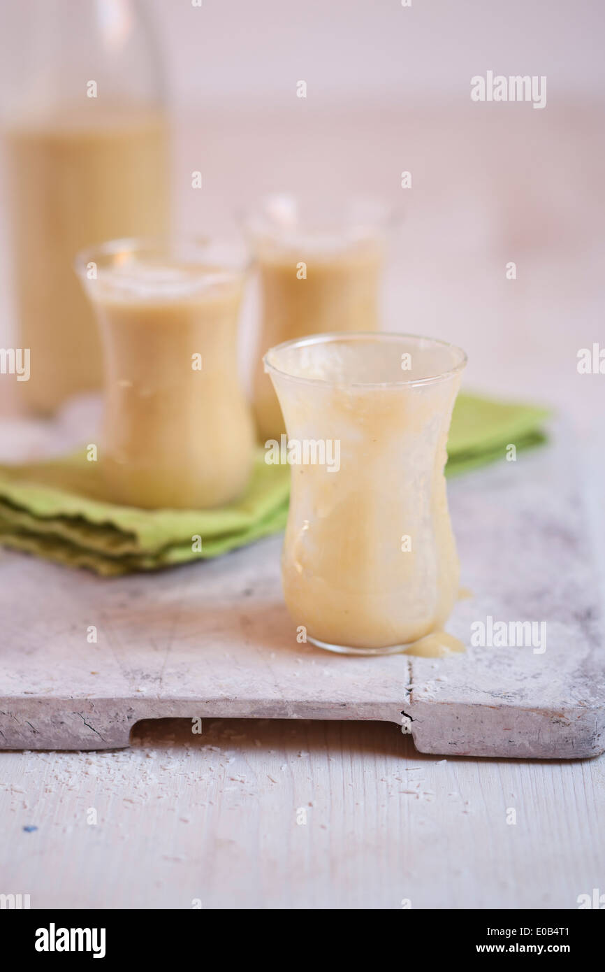 Bicchieri di mango smoothie con noce di cocco essicata su stoffa e scheda di cucina Foto Stock