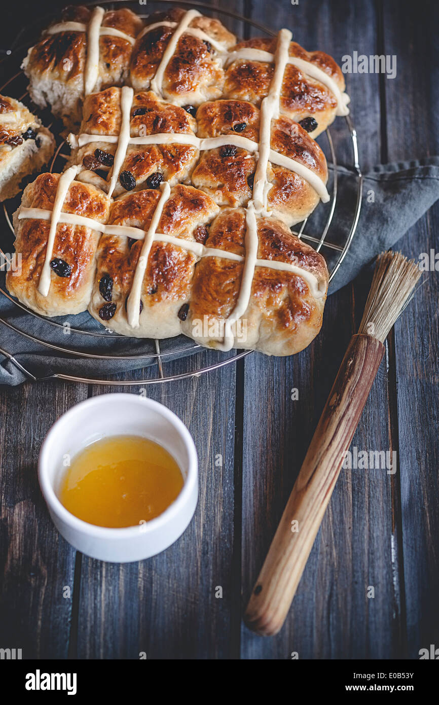 Hot-Cross-panini con uvetta, arancione la smaltatura e la spazzola di pasticceria Foto Stock