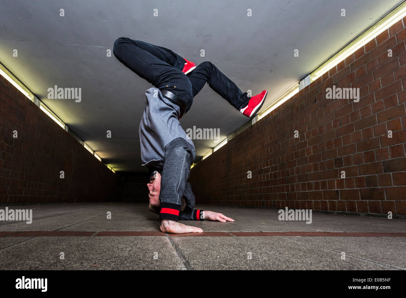 Giovane breakdancer eseguendo un handstand nel sottopassaggio Foto Stock