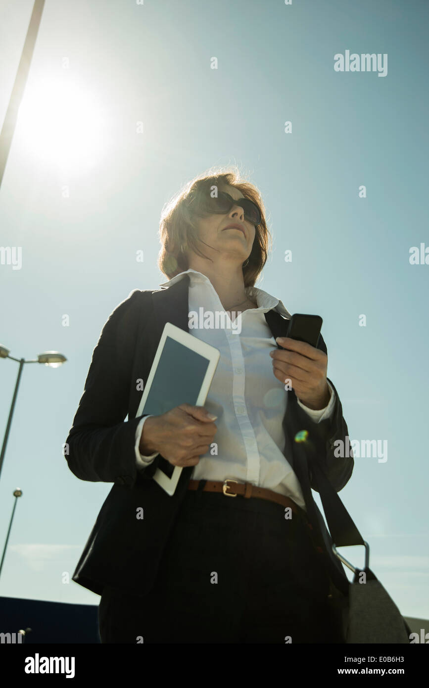 Ritratto di donna di affari con lo smartphone e tablet PC, vista dal basso Foto Stock