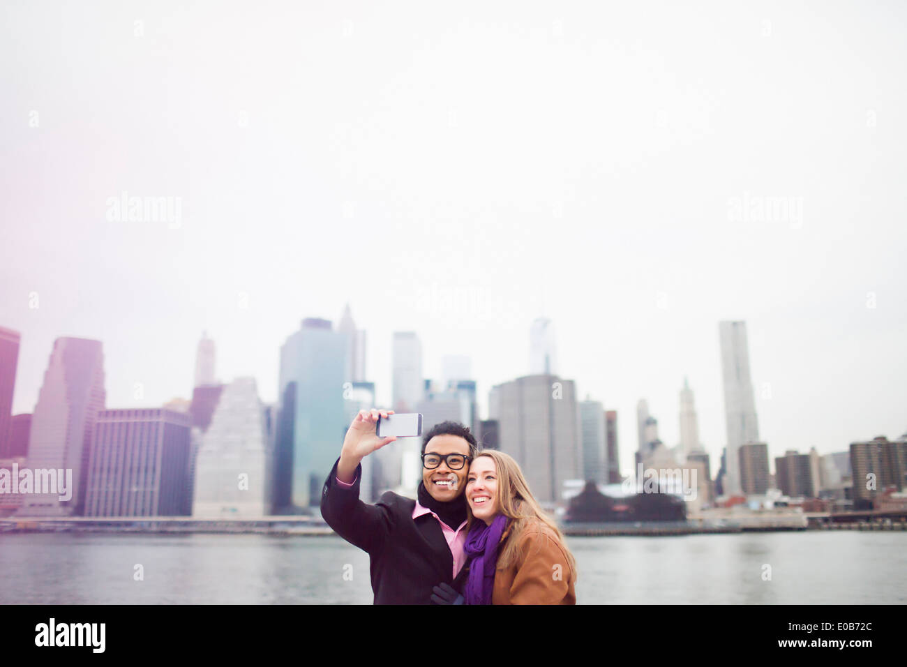 Coppia giovane tenendo selfie con lo skyline di Manhattan, New York, Stati Uniti d'America Foto Stock