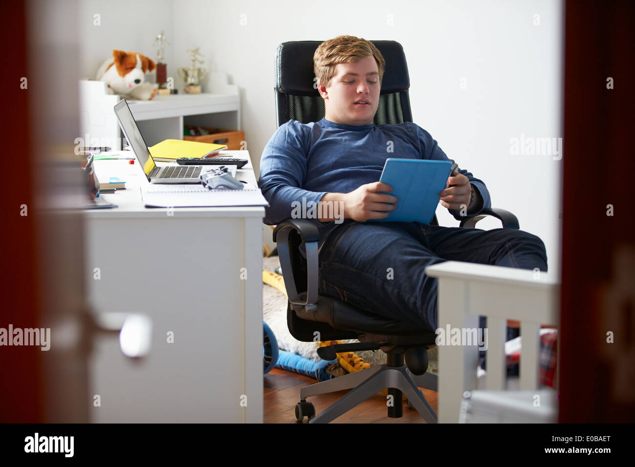 Ragazzo adolescente utilizzando digitale compressa nella camera da letto Foto Stock