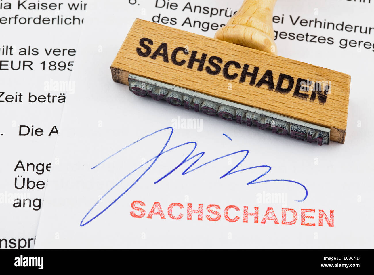 Un francobollo di legno si trova su un documento. Etichetta tedesca: Danni alla proprietà, Ein Stempel aus Holz liegt auf einem Dokument. Deutsche Au Foto Stock