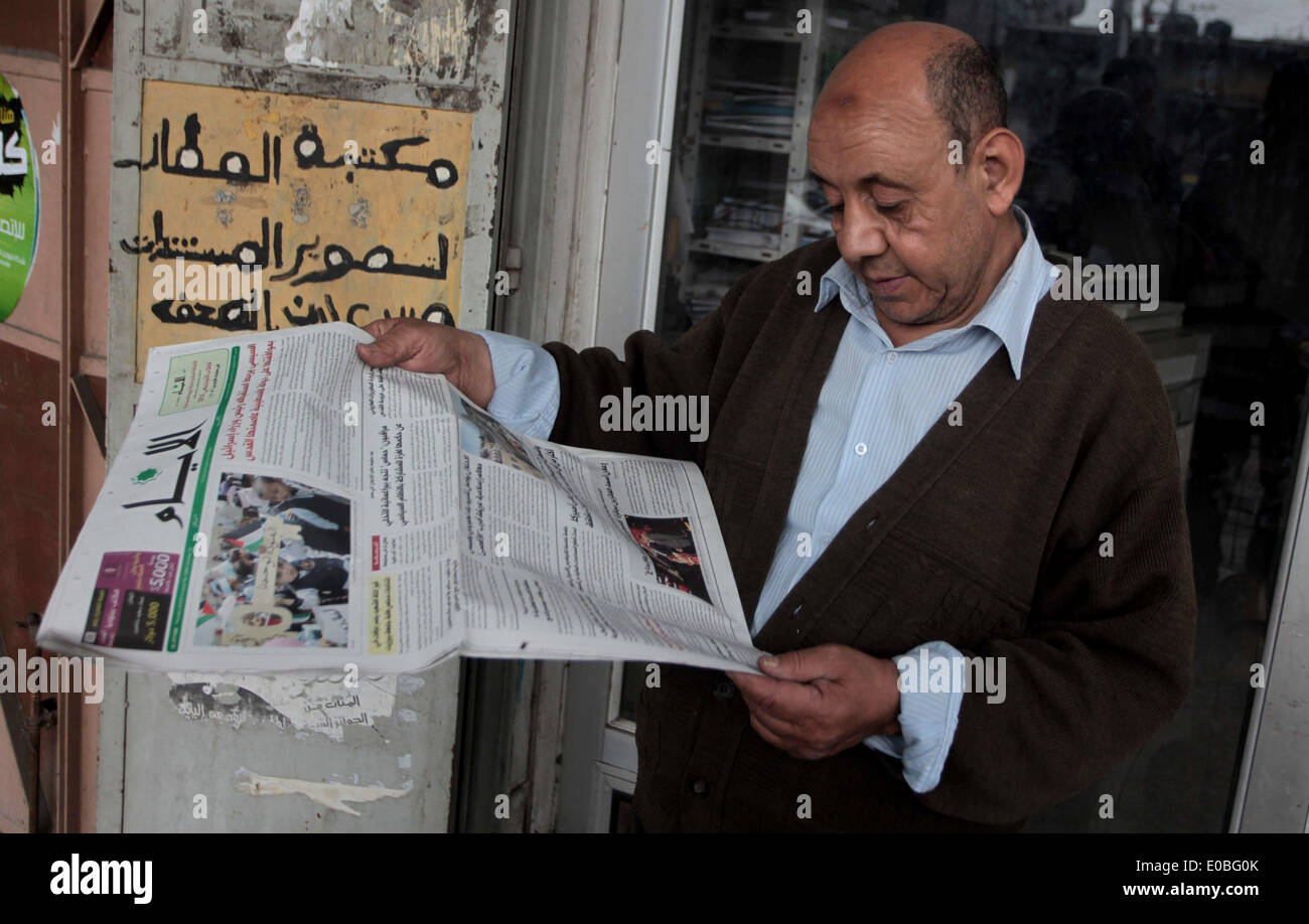 8 maggio 2014 - Deir Al-Balah, Striscia di Gaza, Territori palestinesi - un uomo palestinese legge una copia del Al-Ayyam palestinese quotidiano di Deir al-Balah nel centro della Striscia di Gaza, in data 8 maggio 2014. Il quotidiano palestinese che viene modificato e stampato in Cisgiordania città di Ramallah ha avuto il permesso di Hamas per essere distribuiti nella striscia di Gaza per la prima volta in sette anni dopo il movimento islamista e il western-backed Autorità palestinese hanno firmato una sorpresa accordo di riconciliazione il 23 aprile in una offerta di fine anni di amaro e talvolta sanguinosa rivalità (credito Immagine: © Ashraf Amra/A Foto Stock