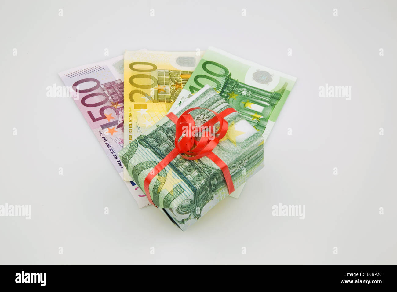 Un pacchetto come presente in euro-banconote smorzato. Dono del denaro e del pacchetto di misure di risparmio., Ein Paket als Geschenk in Euro-Geldschein Foto Stock