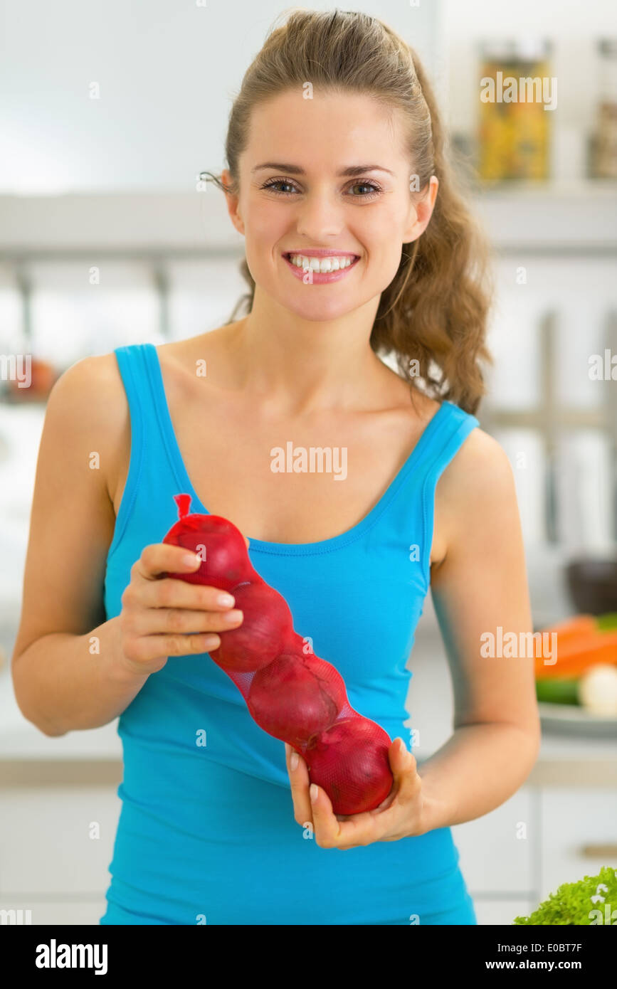 Felice giovane donna con cipolla in cucina Foto Stock