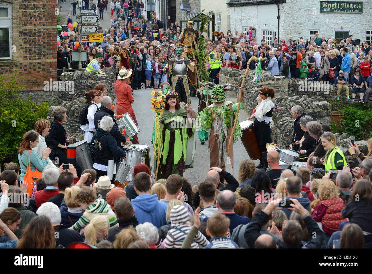 Il Green Man Festival a Clun nello Shropshire. L'uomo Verde e la sua Regina di Maggio attraversano l'antico ponte dopo aver sconfitto la Regina Frost. Foto Stock