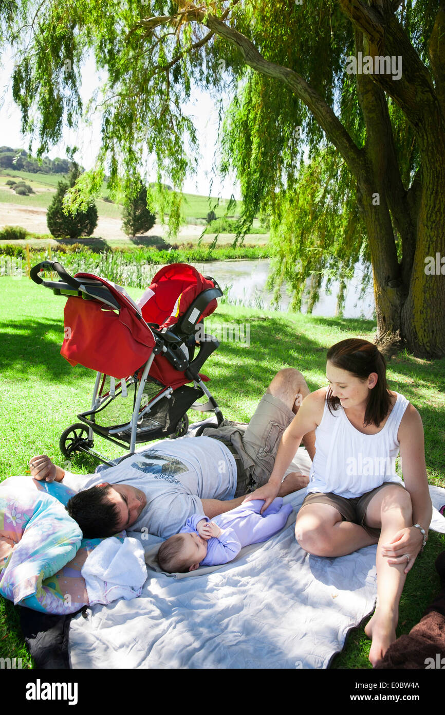 Famiglia relax su una coperta sotto un salice a Rhebokskloof Wine Estate, domenica pomeriggio, Paarl, Sud Africa Foto Stock