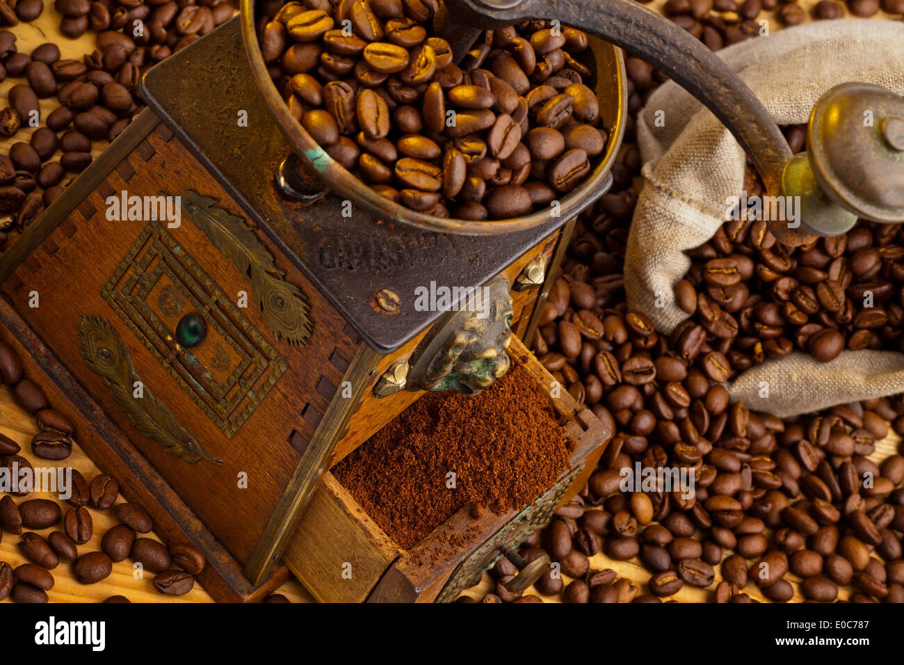 Molti i chicchi di caffè si trovano accanto a un macinino da caffè. Caffè macinato fresco, Viele Kaffeebohnen liegen neben einer Kaffeemuehle. Frisch g Foto Stock
