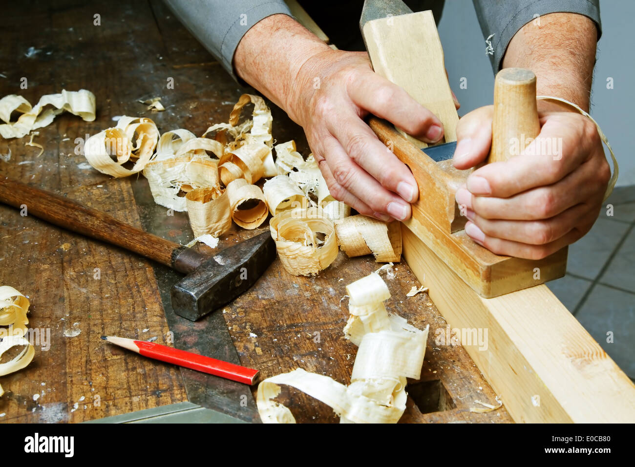 Un falegname con un piano e trucioli di legno in officina., Ein Tischler Mit einem Hobel und Holzspaenen in der Werkstatt. Foto Stock